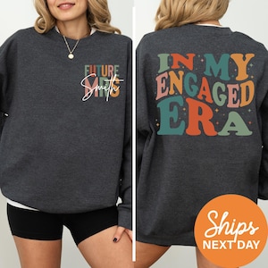 a woman wearing a black sweatshirt with the words in my engaged era printed on it