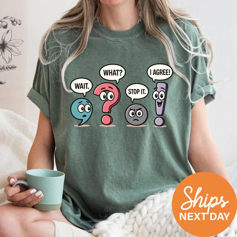 A woman wearing a green t-shirt with a graphic design of four cartoon speech bubbles containing text and symbols, including a question mark, exclamation point, and two speech bubbles with the words "WAIT", "WHAT?", "I AGREE!", and "STOP IT".