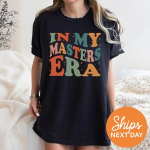 a woman wearing a black shirt that says in my masters era