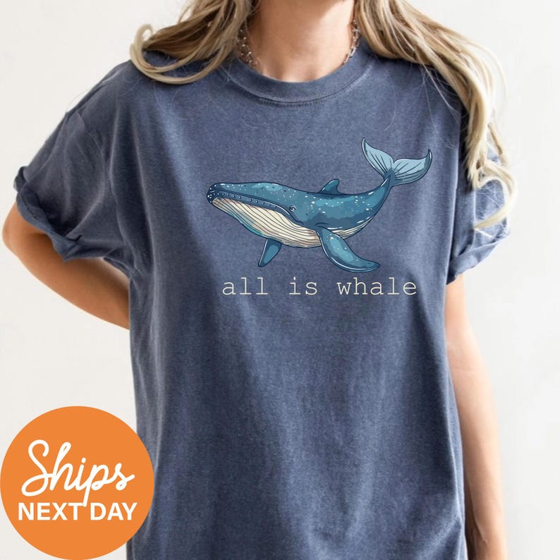 a woman wearing a blue shirt with a whale on it