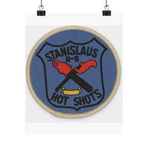 Könnte beinhalten: Runder Aufnäher mit blauem Schilddesign, Text "STANISLAUS R-5" und "HOT SHOTS". Schwarze und rote gekreuzte Fackeln. Der Aufnäher hat einen beigefarbenen Rand.