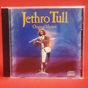 May include: Jethro Tull "Original Masters" CD in a clear jewel case. The album cover features a man playing a flute on a stage with a blue background. The compact disc logo is visible.