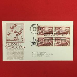 以下が含まれることがあります： 1958年のブリュッセル万国博覧会を記念した白い封筒。茶色のアトミウムのイラスト、テキスト、米国パビリオンが描かれた3セントの米国切手4枚が貼付されている。1958年4月9日のデトロイトの消印が押されている。