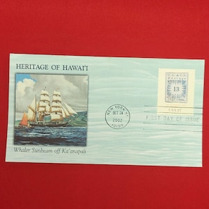 以下が含まれることがあります： 「Heritage of Hawai'i」と題された水色の初日カバー封筒。帆船「Whaler Sunbeam off Ka'anapali」の四角いイラストと、2002年10月24日にニューヨークで消印された37セントの郵便切手が貼付されています。