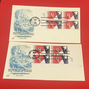 以下が含まれることがあります： アラモの青いインクのイラストと「Republic of Texas Sesquicentennial 1836-1986」の文字が印刷された2枚の白い封筒。各封筒には、1986年3月2日の「First Day of Issue」消印が押された22セントのサンジャシント1836切手が2枚貼られています。