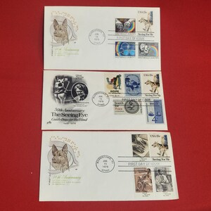 May include: Three white envelopes with stamps and text related to the 50th Anniversary of The Seeing Eye Guide Dogs for the Blind. The envelopes feature illustrations of dogs, people, and the text "First Day of Issue".