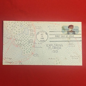 以下が含まれることがあります： 黒い持ち手と「But First, Coffee」の文字が黒い太字でプリントされた白いセラミックマグ。マグカップは、ぼやけた背景に置かれており、居心地の良い環境を暗示しています。