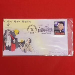 May include: A first day of issue envelope for a 1997 US postage stamp featuring Bela Lugosi as Dracula. The envelope has a drawing of Dracula and a man holding a cross. The envelope is postmarked "Universal City, CA Sept. 30, 1997 91608" and "First Day of Issue at Universal Studios Hollywood".
