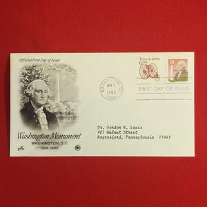 Könnte beinhalten: Offizieller Erstausgabeumschlag mit einem Porträt von George Washington und dem Washington Monument. Enthält Briefmarken mit einem Fahrrad und Washingtons Porträt. Der Umschlag ist vom 6. November 1985 abgestempelt.