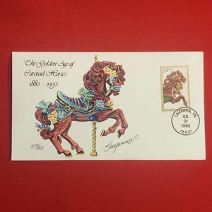 以下が含まれることがあります： メリーゴーランドの馬のイラストが描かれた封筒。テキスト「The Golden Age of Carousel Horses 1880-1930」が印刷されています。32セント切手とペンシルベニア州ラハスカの消印も表示されています。