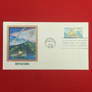 以下が含まれることがあります： ヨットと「American Samoa 33 USA」の文字が描かれた切手が貼られた白い初日カバー。額縁に入ったイラストには、緑の山々とボート、虹が描かれている。円形の消印には「Pago Pago Apr 17 2000」と記されている。