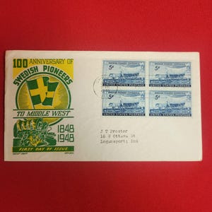 May include: A white envelope celebrating the 100th anniversary of Swedish Pioneers. It has a green and yellow emblem with flags, text, and four 5-cent stamps. The stamps show a wagon and people. The envelope is postmarked.