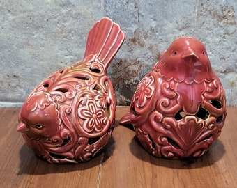 May include: Two red ceramic bird figurines with intricate floral designs. The birds are facing different directions and have a distressed finish.