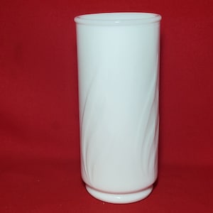 May include: A white ceramic vase with a swirl design. The vase is tall and cylindrical with a rounded base.
