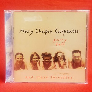 May include: A CD case for Mary Chapin Carpenter's album "Party Doll". The cover is in sepia tones, displaying the artist's name and album title in black and red. Five people are smiling at the bottom, with the text "and other favorites" beneath them.