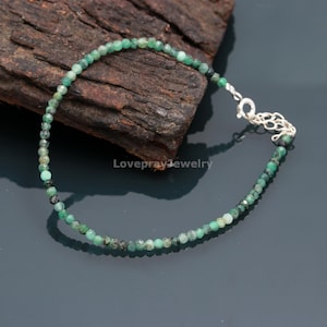 Op de afbeelding: Een delicate groene smaragdstenen kralen armband met een zilveren sluiting. De armband is gemaakt met kleine, gefacetteerde smaragd kralen en is ongeveer 20 cm lang.