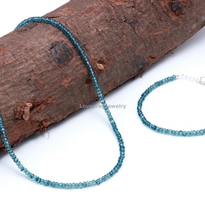 K&ouml;nnte beinhalten: Ein Schmuckset aus blauen Topas-Edelsteinen mit einer Halskette und einem Armband. Die Halskette und das Armband bestehen aus kleinen, runden Perlen.