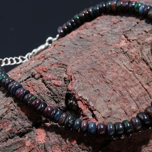May include: A black opal beaded bracelet with a silver clasp. The beads are round and have a dark, iridescent sheen.
