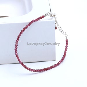 May include: A delicate bracelet made with small, faceted garnet beads and a silver clasp. The bracelet is approximately 7 inches in length.