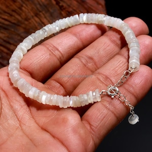 May include: A white moonstone bracelet with a silver clasp. The bracelet is made of small, round beads.