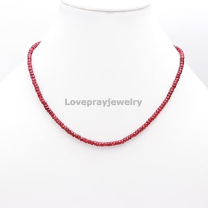 May include: A red gemstone necklace made of small, faceted beads. The necklace is on a white background.