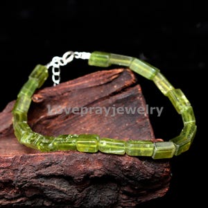 以下が含まれることがあります： 四角いビーズとシルバーの留め具が付いた緑色のペリドットのブレスレットです。