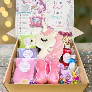 May include: A cardboard box containing a unicorn-shaped white and pink plaque, a pink butterfly-shaped container, a small purple unicorn figurine, various packets of coloured powders, small bottles of liquid, and two instructional cards.