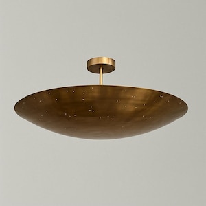 May include: A brass ceiling light fixture with a round, flat, and slightly concave shade. The shade has a dotted pattern and a small round canopy.