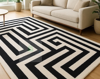 May include: A monochrome geometric rug featuring a black and white maze pattern. The rug is rectangular and lies on a wooden floor. A beige sofa and potted plants are visible in the background.