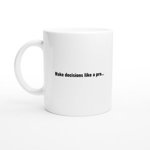 Op de afbeelding: Witte keramische koffiemok met zwarte tekst die "Make decisions like a pro..." luidt.