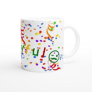May include: White ceramic mug with a colourful confetti design. The mug has the word "Yay!" written on it in green and red letters. There is a green smiley face with a moustache on the mug.