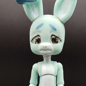 May include: A mint green articulated bunny doll with blue accents on the ears, hands, and feet. The doll has a sad expression with brown eyes. The text "SUPPORT ARTISTS! Legit Kabbit - Maker! SHOP SMALL!" is visible.