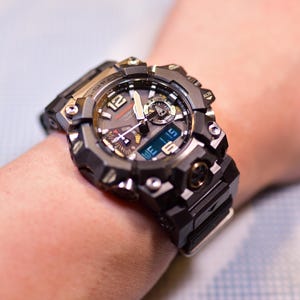 May include: A black and silver wristwatch with a digital display and analog hands. The watch has a large, chunky design with multiple buttons and a black rubber strap.
