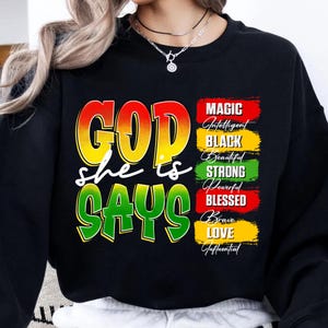 May include: Black sweatshirt with the text "GOD she is SAYS" in yellow, red, and green. The right side features a list of words: Magic, Intelligent, Black, Beautiful, Strong, Powerful, Blessed, Brave, Love, and Influential.
