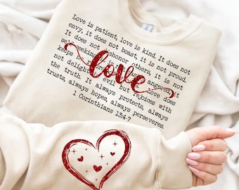 Könnte beinhalten: Beigefarbener Pullover mit einem roten Glitzerherz und einem Zitat aus 1. Korinther 13,4-7 über die Liebe. Das Zitat lautet: "Die Liebe ist geduldig, die Liebe ist gütig. Sie ist nicht neidisch, sie prahlt nicht, sie ist nicht stolz. Sie sucht nicht ihren Vorteil, sie lässt sich nicht reizen, sie trägt keine Rechenschaft über das Böse. Die Liebe freut sich nicht über das Unrecht, sondern freut sich über die Wahrheit. Sie erträgt alles, sie glaubt alles, sie hofft alles, sie erduldet alles. 1. Korinther 13,4-7"