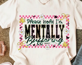 Op de afbeelding: Wit T-shirt met de tekst "Please hold I'm MENTALLY Buffering". Het ontwerp bevat een roze en witte geruite rand, bloemen, vlinders en gele strikken. Een casual kledingstuk voor dagelijks gebruik.