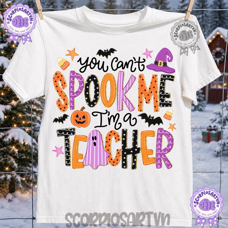 May include: A white short-sleeve t-shirt featuring the colorful text You can't SPOOK ME I'm a TEACHER. The design includes orange, purple, and black patterned letters, a jack-o'-lantern, a purple witch hat, a ghost, bats, and candy corn icons.