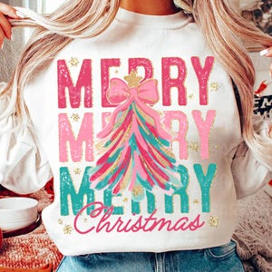May include: White sweatshirt with a pink, teal, and gold Christmas tree design and the text "Merry Merry Merry Christmas".