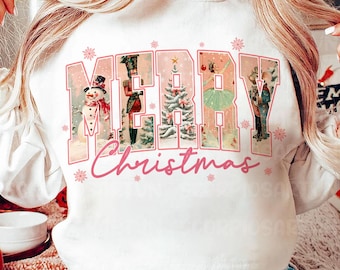 May include: White sweatshirt with a pink "Merry Christmas" graphic featuring vintage illustrations of a snowman, a nutcracker, a Christmas tree, a ballerina, and a soldier.