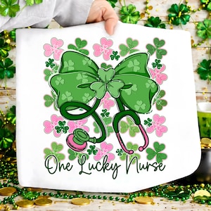 May include: White towel featuring a green bow with shamrock details and a stethoscope. Pink and green shamrocks surround the bow and stethoscope. The text "One Lucky Nurse" is written in green script below the stethoscope.