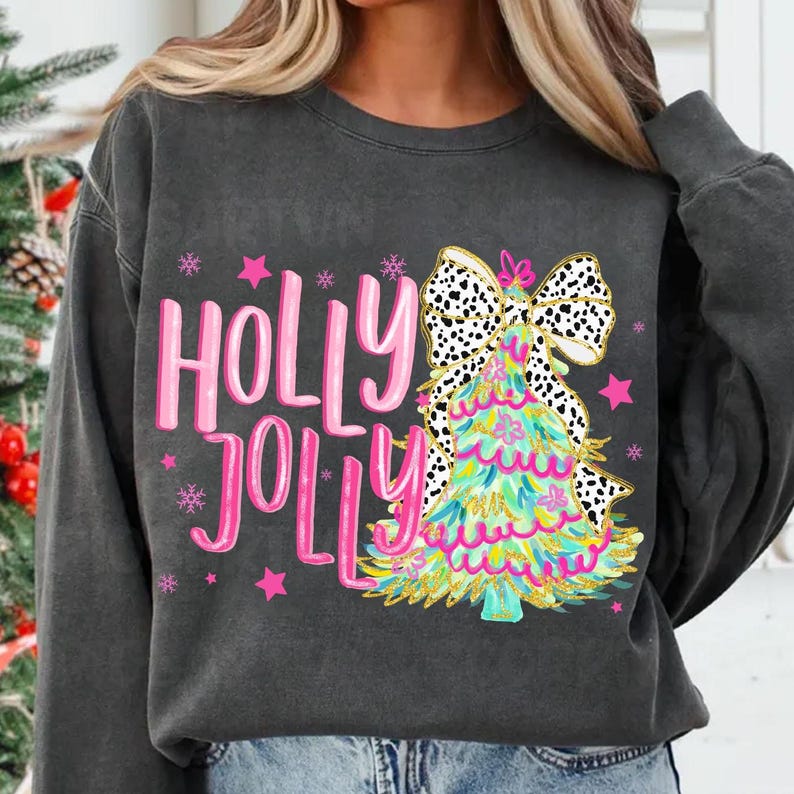 May include: A black sweatshirt with a pink and green Christmas tree design and the words "Holly Jolly" in pink.