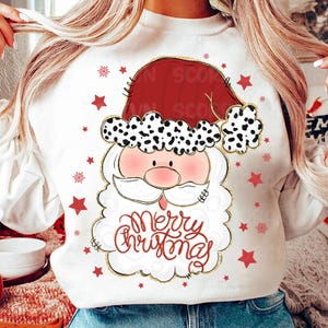 May include: White sweatshirt with a cartoon Santa Claus wearing a red hat with black and white spots. The Santa Claus has a white beard and mustache and is holding a sign that says "Merry Christmas". The sweatshirt is decorated with red stars.