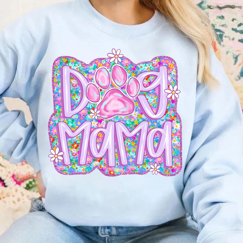 May include: Light blue sweatshirt with a purple and pink graphic design that says "Dog Mama" with a paw print in the middle. The graphic is surrounded by a floral pattern.