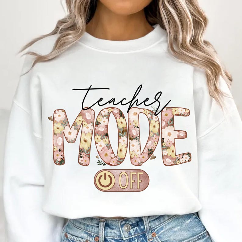 May include: White sweatshirt with the text "Teacher Mode" in floral letters with a pink and yellow color scheme. The word "Mode" is larger than the word "Teacher". Below the text is a pink and gold power button with the word "OFF" written on it.