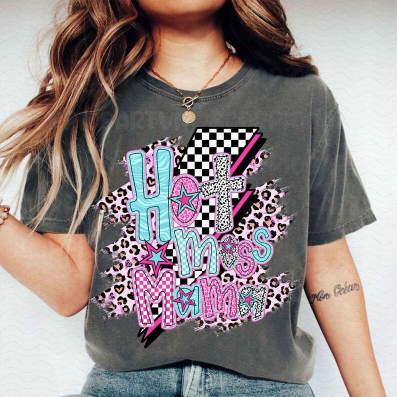 May include: A gray t-shirt with a graphic design featuring the text "Hot Mess Mama" in pink, blue, and white with a checkered pattern, stars, and leopard print.