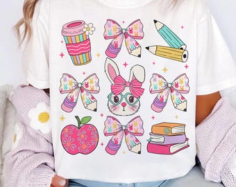 May include: White t-shirt with a pink bunny wearing glasses and a bow, surrounded by pink bows, pencils, a coffee cup, an apple, and books. The design is in a cartoon style.