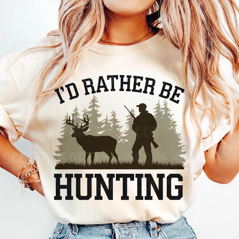 May include: A white t-shirt with the text "I'd rather be hunting" in black. The design features a silhouette of a hunter with a rifle and a deer in a forest setting.