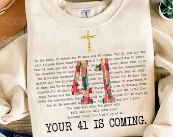 Könnte beinhalten: Ein beiger Pullover mit einem goldenen Kreuz und einer bunten Grafik der Zahl 41. Der Text "In der Bibel regnete es 40 Tage und 40 Nächte. Tag 41 kam und der Regen hörte auf. Mose verpflichtete sich..." ist auf dem Pullover gedruckt. Der Text "YOUR 41 IS COMING." ist unten auf dem Pullover gedruckt.