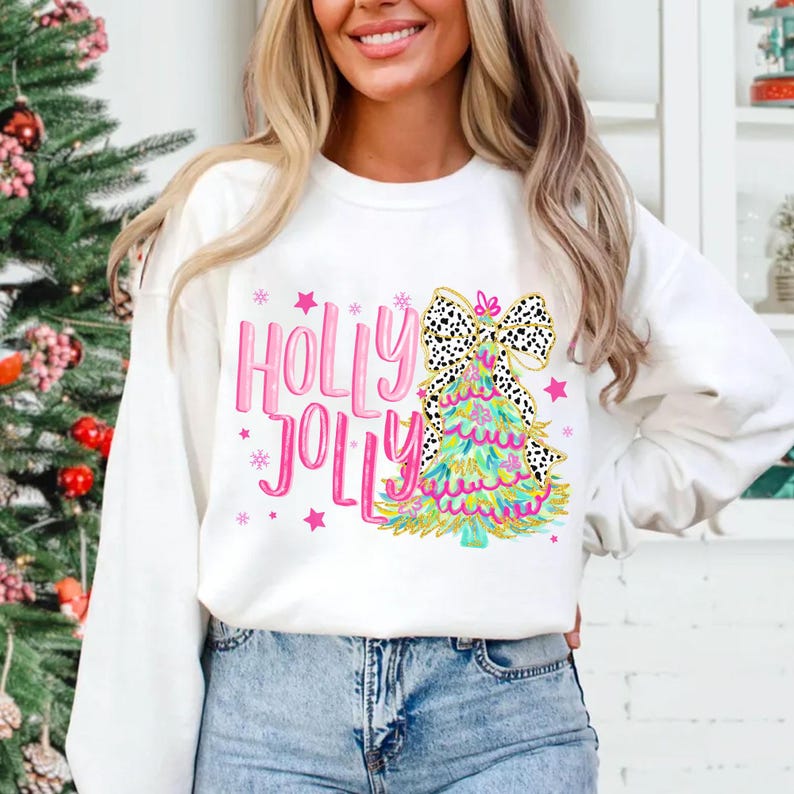 May include: White Christmas sweatshirt with a pink and green Christmas tree design and the text "Holly Jolly" in pink.