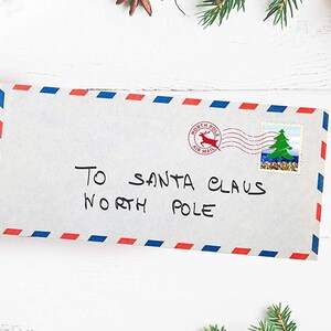 May include: A white envelope with red and blue stripes along the edges. The envelope is addressed to "To Santa Claus North Pole" with a red and blue "North Pole Air Mail" stamp with a reindeer and a green Christmas tree stamp.